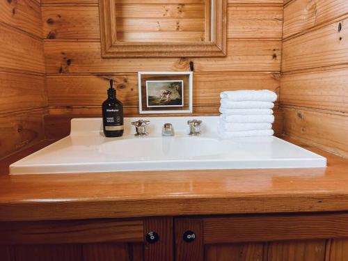 a bathroom sink with a bottle of wine on it at Barefoot Bungalow in Bicheno