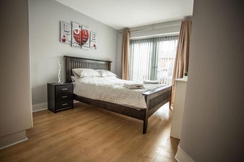 a bedroom with a bed with a wooden floor and a window at Diamond Apartment in Belfast