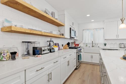 a white kitchen with white cabinets and white counter tops at Golf - Beach - Legoland - Shopping - Dining in Carlsbad