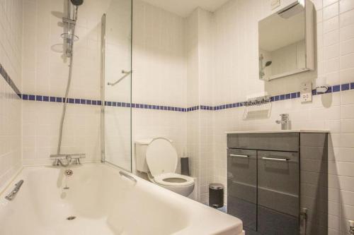 a bathroom with a tub and a toilet and a sink at Diamond Apartment in Belfast