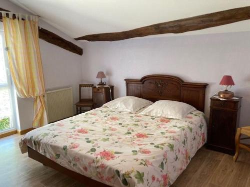a bedroom with a bed with a floral bedspread at Ancienne ferme restaurée avec charme, vergers de mirabelles, borne électrique, proche Lac de Madine - FR-1-585-7 in Buxières-sous-les-Côtes