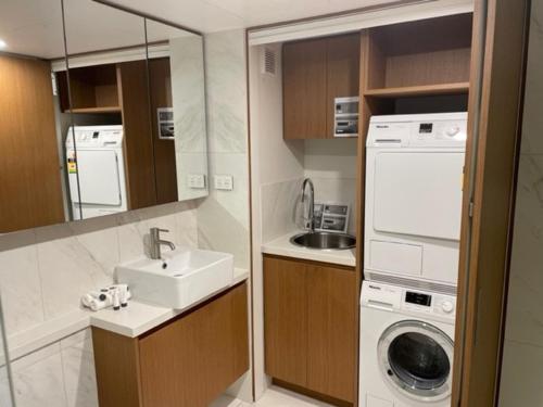 a small kitchen with a sink and a washing machine at Il Palazzo Holiday Apartments in Cairns