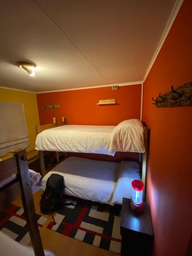 a bedroom with two beds and a red wall at Konkashken Lodge in Torres del Paine