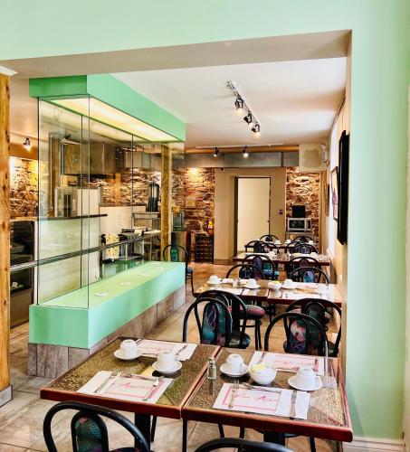 a restaurant with tables and chairs and a kitchen at Auberge Le St-Alexis in La Baie