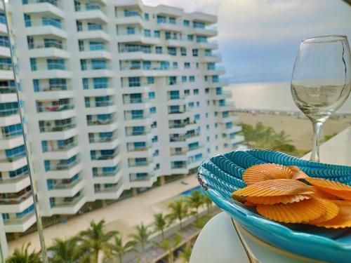 une assiette de nourriture et un verre de vin sur une table près de la plage dans l'établissement Morros Epic, à Carthagène des Indes