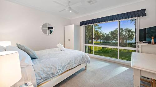 een slaapkamer met een bed en een groot raam bij Sunset Beach Luxury 24 in Soldiers Point