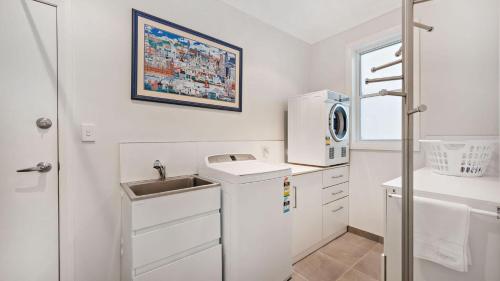 a small white kitchen with a sink and a microwave at Sunset Beach Luxury 24 in Soldiers Point