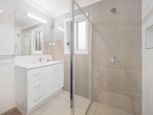 a white bathroom with a shower and a sink at 61 Myack Street in Berridale