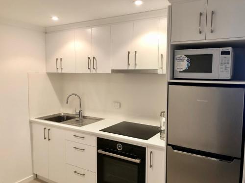 a kitchen with white cabinets and a sink and a microwave at Arlberg 204 Ski-In Ski-Out Studio Apartment in Mount Buller