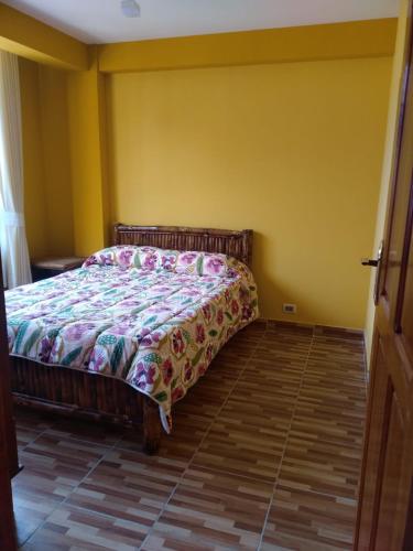 a bedroom with a bed in a yellow room at ACOGEDOR DEPARTAMENTO in Coroico