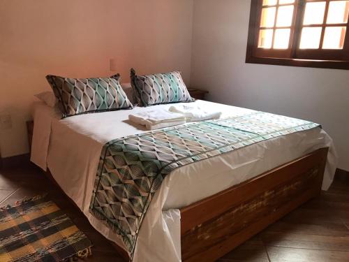 - une chambre dotée d'un grand lit avec des draps et des oreillers blancs dans l'établissement Chalés do Alferes, à Tiradentes