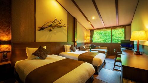 a hotel room with two beds and a desk at Hachimantai Mountain Hotel & Spa in Hachimantai