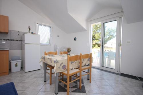 a kitchen with a table with chairs and a refrigerator at Apartments with a parking space Pirovac, Sibenik - 6246 in Pirovac