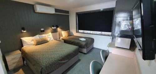 a small room with two beds and a window at Goldrush Motel Young CBD in Young