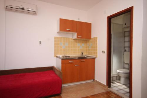 a bathroom with a red bed and a sink and a toilet at Apartments by the sea Tkon, Pasman - 6221 in Tkon