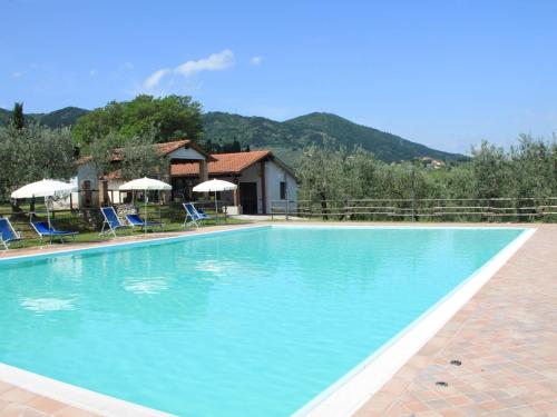 une grande piscine bleue avec des chaises et des parasols dans l'établissement Belvilla by OYO La Casa dei Due Olivi, à Quarrata