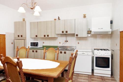 a kitchen with a wooden table and white appliances at Apartments by the sea Veli Iz, Iz - 6255 in Veli Iž