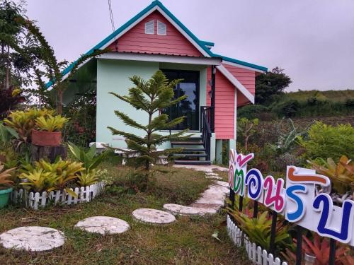 una piccola casa rosa con un cartello di fronte di ภูร่องลม ฟาร์ม a Phetchabun