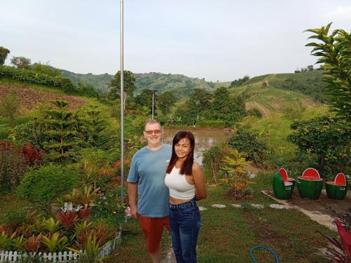 un hombre y una mujer de pie en un jardín en ภูร่องลม ฟาร์ม en Phetchabun