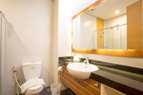 a bathroom with a toilet and a sink and a mirror at Life Hotel Mayjend Sungkono in Dukuhpakis