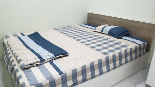 Una cama con sábanas y almohadas azules y blancas. en Era Apartment Xuân Thuỷ, en Hanói