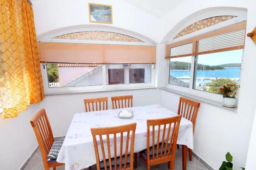 una sala da pranzo con tavolo e sedie e due finestre di Apartments by the sea Brgulje, Molat - 6250 a Brgulje