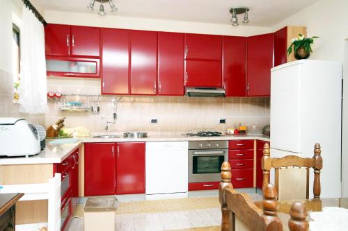 eine rote Küche mit weißen Geräten und roten Schränken in der Unterkunft Apartments by the sea Brgulje, Molat - 6241 in Brgulje
