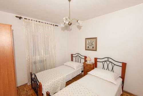 two beds in a room with white walls at Apartments with a parking space Molat - 6249 in Molat