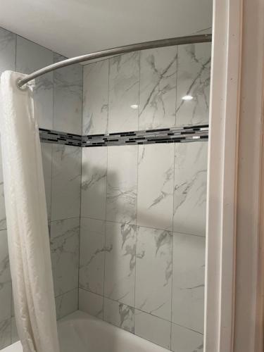 bagno con doccia e piastrelle in marmo bianco di Travelodge by Wyndham Fairplex Pomona a Pomona