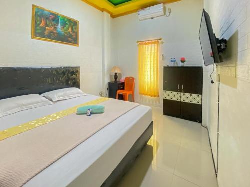 a bedroom with a bed and a television in it at Hotel Karunia 2 Jailolo in Porniti