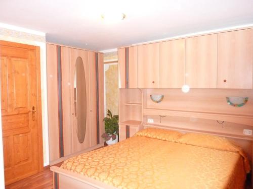 1 dormitorio con 1 cama y armario de madera en Appartamento Stumiaga di Fiavè, en Fiavè
