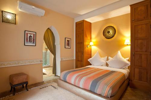 een slaapkamer met een bed, een stoel en een raam bij Riad Enchanté in Marrakesh