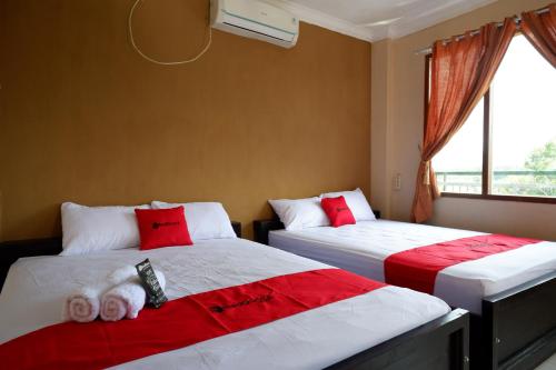 a bedroom with two beds with red and white pillows at RedDoorz At Telaga Mulya Hotel Wates in Yogyakarta