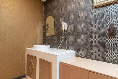 a bathroom with a sink and a phone on the wall at Urbanview Hotel Good Palembang by RedDoorz in Talang Kelapa