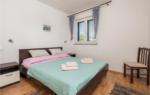 een slaapkamer met een bed, een stoel en een raam bij 2 Bedroom Beautiful Apartment In Stara Novalja in Stara Novalja