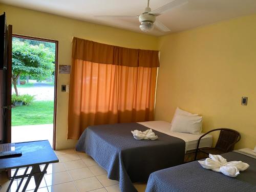 Habitación de hotel con 2 camas y ventana en Hotel Real Alaska, en Liberia