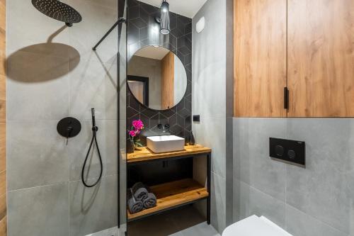 ein Bad mit einer Dusche, einem Waschbecken und einem Spiegel in der Unterkunft Loftowe Love in Kołobrzeg