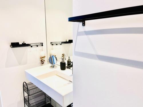 La salle de bains blanche est pourvue d'un lavabo et d'un miroir. dans l'établissement Floating Home Nr 1a, à Laboe