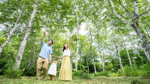 a family standing in the woods with their hands in the air at Hachimantai Mountain Hotel & Spa in Hachimantai