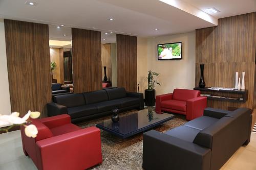 a living room with a couch and red chairs at Summit Hotel Monaco in Guarulhos