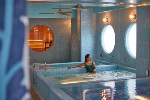 una mujer en un jacuzzi en una piscina en 8 Hotel Shonan Fujisawa, en Fujisawa