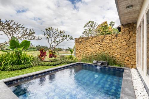 einen Pool vor einer Steinmauer in der Unterkunft New Private Pool Villa - Villa Kita Ubud in Ubud