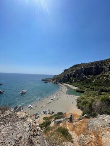 a beach with a group of people and a boat at Arbutus - Relaxing apartment with Fantastic Views in Georgioupolis