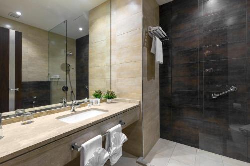 a bathroom with a sink, toilet, and shower stall at Sulaf Luxury Hotel in Amman