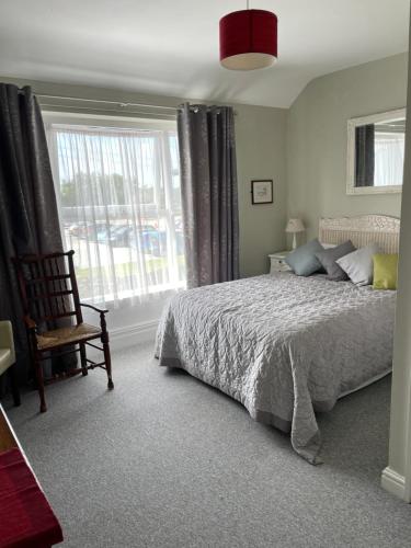 um quarto com uma cama, uma cadeira e uma janela em The Penrhos Arms Hotel em Llanfairpwllgwyngyll