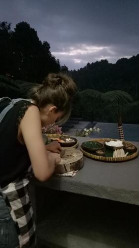 a woman is leaning over a table with cakes at BINTANG MUNDUK in Munduk