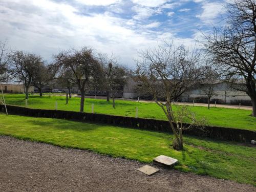 un parque con césped verde, árboles y una pared en Chambre chez l'habitant 1 en Biville-la-Baignarde