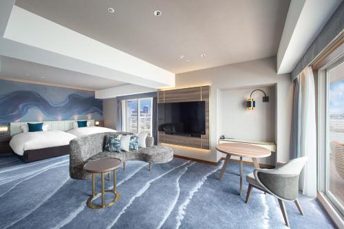 a hotel room with a bed and a desk and chairs at Kobe Meriken Park Oriental Hotel in Kobe