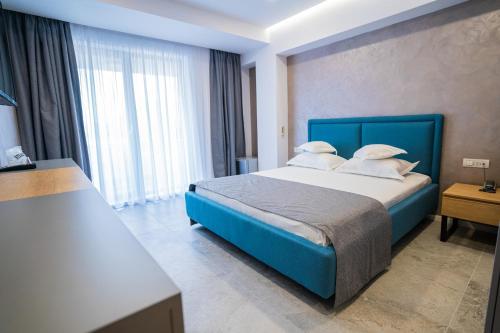 1 dormitorio con cama azul y ventana grande en Hotel Prestige, en Mamaia