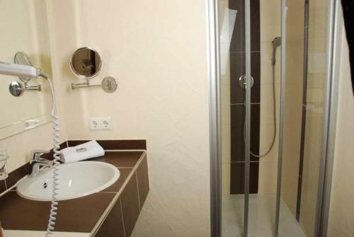 ein Bad mit einem Waschbecken und einer Dusche in der Unterkunft Gasthaus Hotel Adler in Endingen